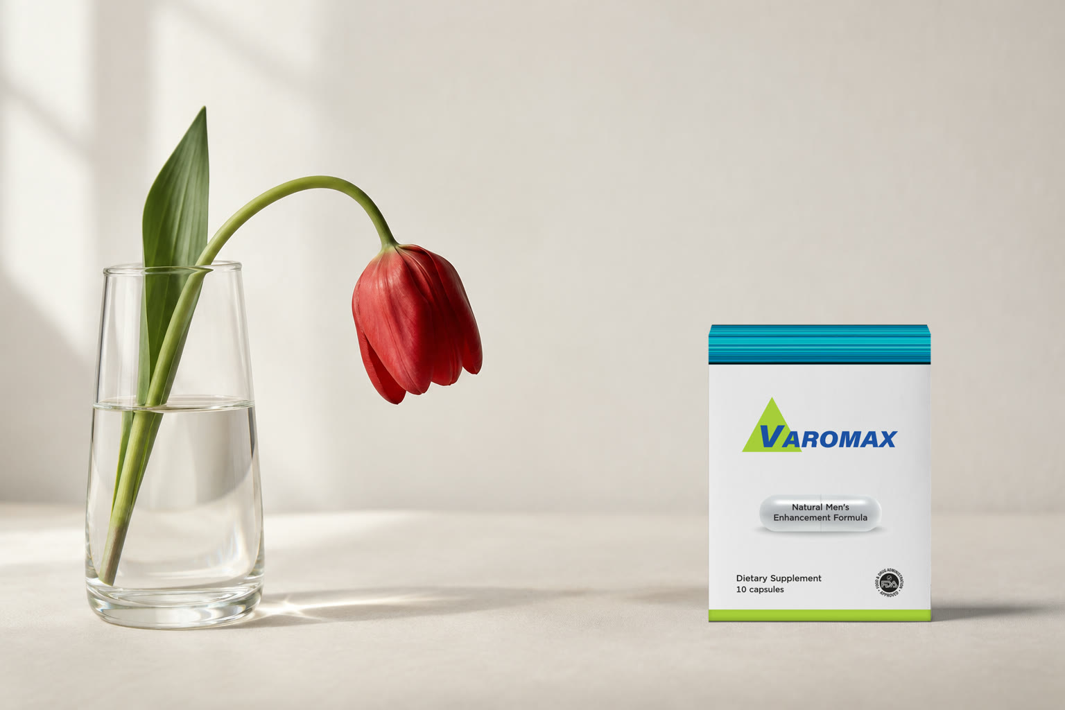 A single red tulip drooping over the rim of a glass vase of water, next to a box of Varomax capsules